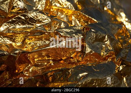 Textur eines dünnen zerknittert Blatt Folie. Hintergrund zerknitterte Folie. Fotofolie auf Lager. Farbe: Gold, Chrom. Stockfoto