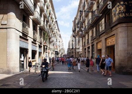 Blick auf die Menschen, die auf einer der engen Einkaufsstraßen namens 'Carrer de Ferran' im Stadtteil 'Ciutat Vella' (Gotisches Viertel) in Barcelona spazieren gehen. Das ist es Stockfoto