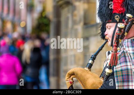 Edinburgh, Schottland - Dez 2018. Schottischer Dudelsackspieler in traditionellem roten und schwarzen Tartankleid, der Dudelsack auf der Royal Mile spielt. Stockfoto