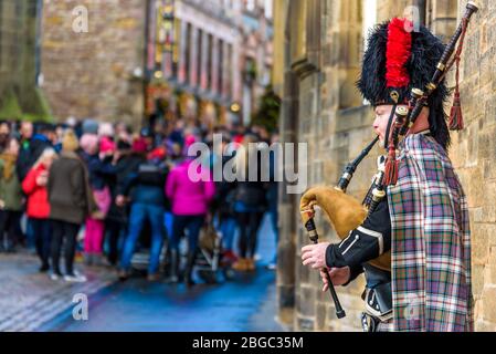 Edinburgh, Schottland - Dez 2018. Schottischer Dudelsackspieler in traditionellem roten und schwarzen Tartankleid, der Dudelsack auf der Royal Mile spielt. Stockfoto