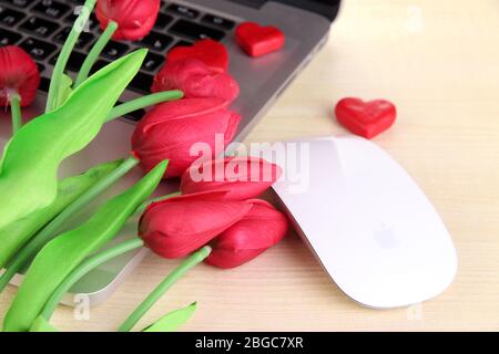 Computer mit roten Herzen und Blumen auf dem Tisch aus nächster Nähe Stockfoto