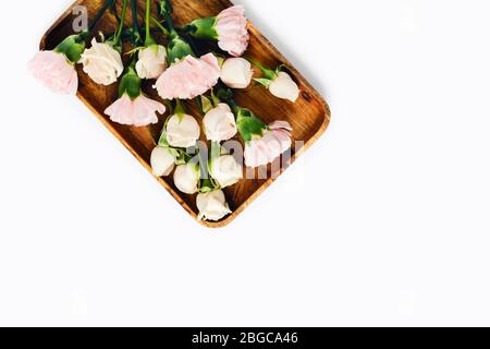 Weiße und rosa Rosen auf einem Holztablett auf weißem, isoliertem Hintergrund. Stockfoto