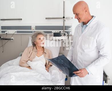 Frau ältere Patientin erhält eine ärztliche Beratung, die im Bett auf der Station liegt. Pflege älterer Patienten Stockfoto