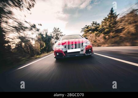 Rote Rennwagen Landschaftfahrt im Sonnenuntergang, Vorderansicht Stockfoto