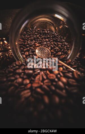 Kaffeebohnen verschüttet aus einem Glas, dunkler Hintergrund Stockfoto