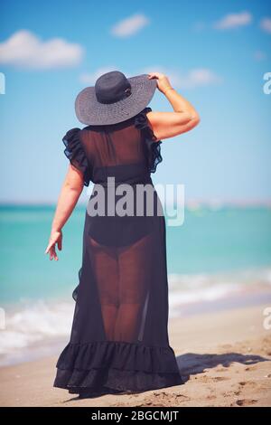 Schöne Übergrößen erwachsenen Frau genießt die Sommerferien zu Fuß entlang der Sandstrand Stockfoto