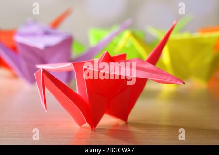 Origami Kraniche auf Holztisch, auf hellem Hintergrund Stockfoto