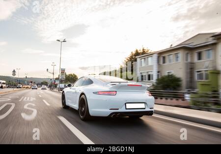 Fahrt mit dem weißen Sportwagen in die Stadt, Blick von hinten Stockfoto