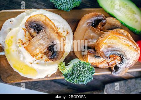 Kalorienarme englische Frühstück Eier Benedikt mit gebratenen Pilzen und Brokkoli. Bleiben Sie zu Hause und kochen. Stockfoto