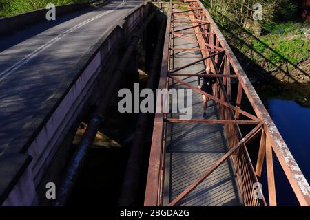 Ein Mann, der im Rahmen seiner Schleusenübung über die Fußgängerbrücke des River Aire in Shillington joggt Stockfoto