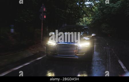 Autofahren auf der regnerischen Straße mit weißen Xenon-Lichtern in der Dunkelheit Stockfoto