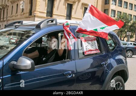 Beirut, Libanon. 21. April 2020. Regierungsfeindliche Demonstranten demonstrieren in einem Konvoi mit Autofahrern, die ihre Hupen hupen und die Nationalflagge schwenken und sich mit Gesichtsmasken aus den Fenstern lehnen, während sie durch das Zentrum von Beirut fahren, um gegen die sich verschlechternden Lebensbedingungen zu protestieren und den Rückgang des Lebensstandards zu unterstreichen, der gewesen ist Verschärft durch den Ausbruch der Sperrung des Coronavirus und um den Druck auf die Politiker aufrechtzuerhalten, seit im Oktober Massenproteste ausbrachen. Kredit: amer Ghazzal/Alamy Live Stockfoto