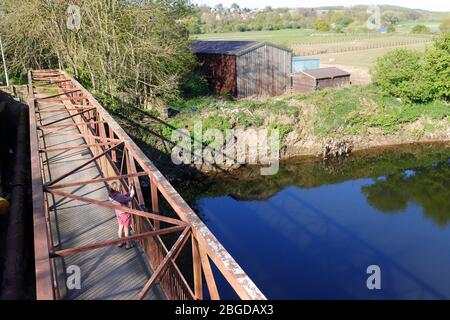 Eine Dame macht ein Foto mit ihrer Handykamera von der Fußgängerbrücke über den Fluss Aire in Leeds Stockfoto