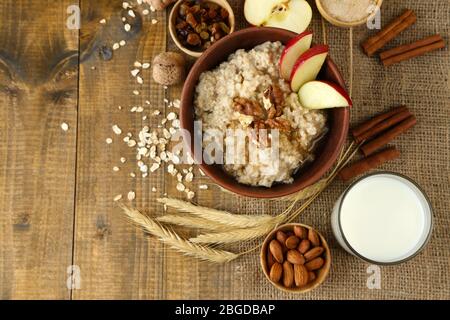 Leckere Haferflocken mit Nüssen und Äpfeln auf Holztisch Stockfoto