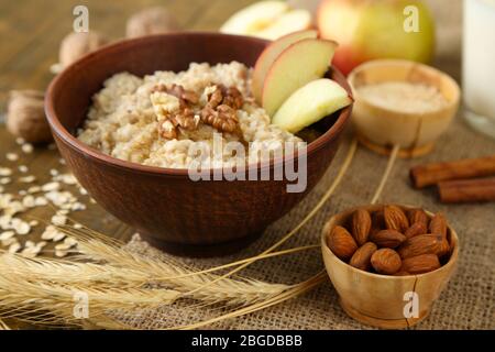 Leckere Haferflocken mit Nüssen und Äpfeln auf Holztisch Stockfoto