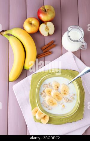 Leckere Haferflocken mit Bananen und Milch auf Holztisch Stockfoto