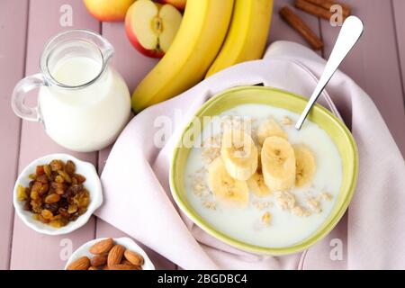 Leckere Haferflocken mit Bananen und Milch auf Holztisch Stockfoto
