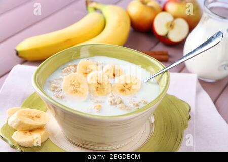 Leckere Haferflocken mit Bananen und Milch auf Holztisch Stockfoto