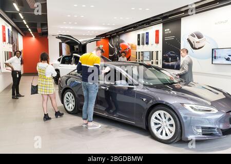 Kunden, die im Showroom der Tesla Automotive Company in der Mall am Cribbs Causeway, Bristol, Großbritannien, stöbern Stockfoto