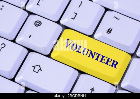 Eine Tastatur mit dem Wort VOLUNTEER in blauer Schrift auf einer gelben ENTER-Taste. Konzept der Freiwilligenarbeit. England, Großbritannien Stockfoto