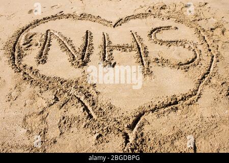 NHS geschrieben in Sand in einer Herzform, um Liebe zu illustrieren das National Health Service Konzept während Covid-19 Pandemie im Jahr 2020. Großbritannien Stockfoto