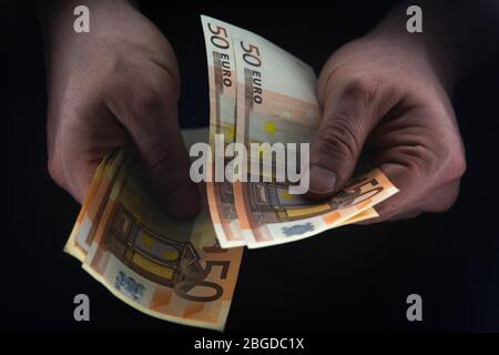 Mann mit 50 EURO-Scheinen in einem dunklen Raum, illegales Geld, Habgier-Konzept. Stockfoto