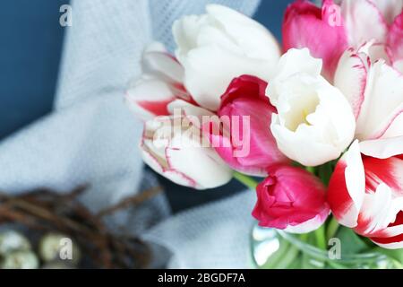 Komposition mit Ostereiern und schönen Tulpen in Glaskrug auf farbigem Holzhintergrund Stockfoto