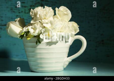 Schöne Frühlingsblumen in Tasse auf grünem Hintergrund Stockfoto