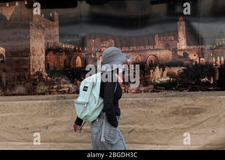 Ein Fußgänger, der aufgrund der COVID-19-Coronavirus-Pandemie eine Gesichtsmaske trägt, kommt an einem Plakat vorbei, auf dem der befestigte Turm von David, auch bekannt als Jerusalem Citadel in der Innenstadt von West-Jerusalem Israel, abgebildet ist Stockfoto