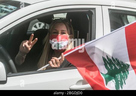 Beirut, Libanon. 21. April 2020. Regierungsfeindliche Demonstranten demonstrieren in einem Konvoi mit Autofahrern, die ihre Hupen hupen und die Nationalflagge schwenken und sich mit Gesichtsmasken aus den Fenstern lehnen, während sie durch das Zentrum von Beirut fahren, um gegen die sich verschlechternden Lebensbedingungen zu protestieren und den Rückgang des Lebensstandards zu unterstreichen, der gewesen ist Verschärft durch den Ausbruch der Sperrung des Coronavirus und um den Druck auf die Politiker aufrechtzuerhalten, seit im Oktober Massenproteste ausbrachen. Kredit: amer Ghazzal/Alamy Live Stockfoto