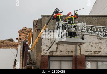 Feuerwehrleute an einem Straßenkran, die an einem eingestürzten Gebäude arbeiten. Stockfoto