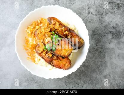 Frittierte scheiben Pangasius Fisch mit Knoblauch, mit braunem Reis serviert. Stockfoto