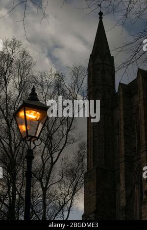 Moody-Bild zeigt eine einzige alte Stil Straßenbeleuchtung in der Dämmerung mit der Silhouette eines Baumes und Kathedrale Turm auf einer Seite Stockfoto