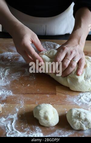 Konzept der hausgemachten Küche. Weibliche Hände bereiten kleine Kugeln von frischen hausgemachten Pizzateig auf bemehlten Holzbrett. Nahaufnahme. Italienische Küche. Stockfoto