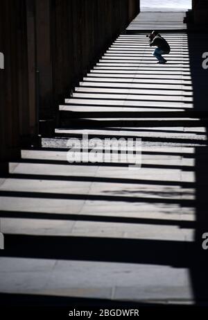 21. April 2020, Berlin: Ein Mann fotografiert in einer Kolonnade vor der Alten Nationalgalerie und dem Neuen Museum auf der Museumsinsel. Seit Mitte März sind die 170 Staats-, Stadt- und Privatmuseen Berlins geschlossen. Die zum Weltkulturerbe erklärte Museumsinsel im Zentrum Berlins wurde zuletzt jährlich von gut drei Millionen Menschen besucht. Unter der Voraussetzung, dass die jeweiligen Häuser den hygienischen Anforderungen und den in der Corona-Krise geltenden Fernabsatzvorschriften entsprechen, erwägt der Berliner Senat die Wiedereröffnung der Museen am 11. Mai 2020 Stockfoto