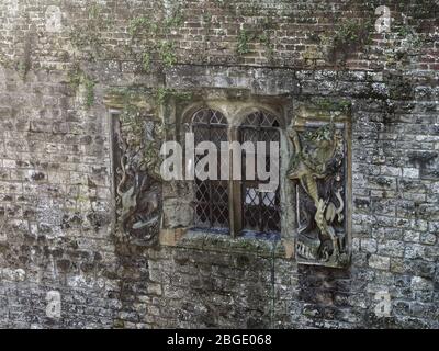 Bogenfenster mit Ornamenten von Löwen- und Einhorn-Skulpturen auf einer Steinmauer im Eltham Palace. Stockfoto