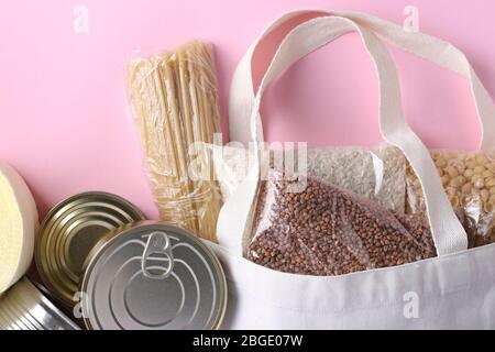 Textil Lebensmitteltasche mit Lebensmitteln Krise Lebensmittelvorrat für Quarantäne Isolationsperiode auf rosa Hintergrund. Reis, Buchweizen, Nudeln, Dosenfutter. Essen Stockfoto