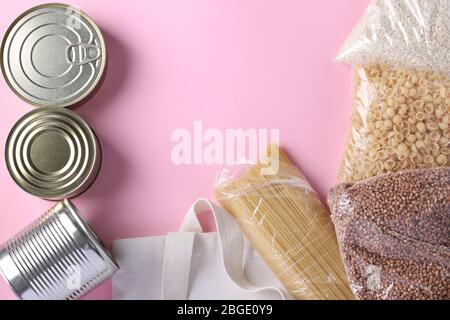 Textil Lebensmitteltasche mit Lebensmitteln Krise Lebensmittelvorrat für Quarantäne Isolationsperiode auf rosa Hintergrund. Reis, Buchweizen, Nudeln, Dosenfutter. Essen Stockfoto