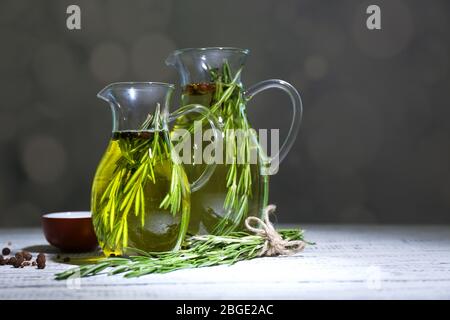 Ätherisches Öl mit Rosmarin in Glaskrug, auf dunklem Hintergrund Stockfoto