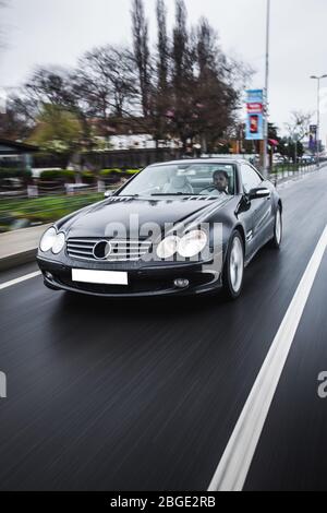 Schwarze Limousine mit weißen Frontleuchten auf der Autobahn Stockfoto