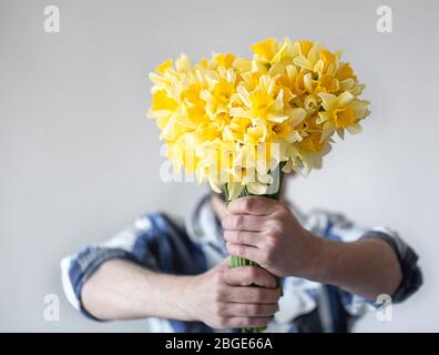 Der Mann bedeckt sein Gesicht mit einem Blumenstrauß. Stockfoto