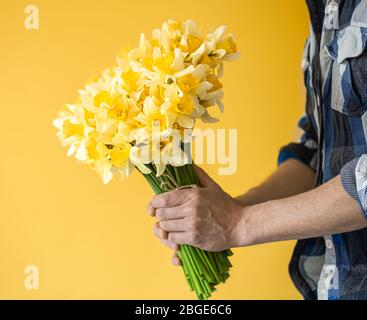 Hipster Mann auf gelbem Hintergrund in einem Hemd und einem Blumenstrauß. Stockfoto