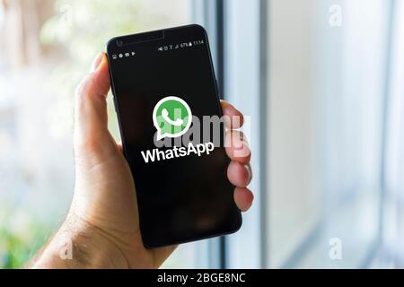 Junger Mann hält Handy mit WhatsApp Logo auf dem Bildschirm. Soziale Netzwerke. BUENOS AIRES, ARGENTINIEN - 19. DEZEMBER 2018. Stockfoto