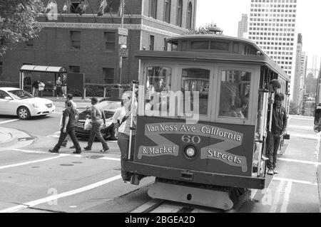 Straßenbahn San Francisco Straßenbahn Vanness Market Street Leute, die sich von den Leuten hängen lassen laufen Touristenflaggen laufen Läufer Board Elektrische Spazierfahrt Stockfoto