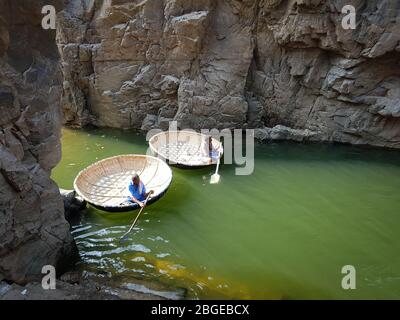 Zwei Männer warten auf einem Korakel, das im Fluss Cauvery auf Wasser schwimmt Stockfoto