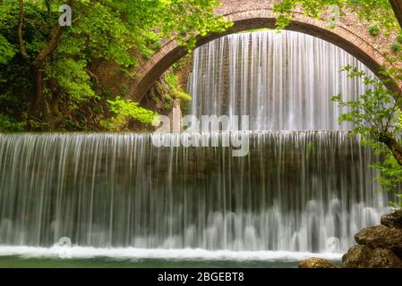 Atemberaubende Frühlingslandschaft.Paleokarya, alt, Stein, Bogenbrücke, zwischen zwei Wasserfällen. Präfektur Trikala, Thessalien, Griechenland Stockfoto