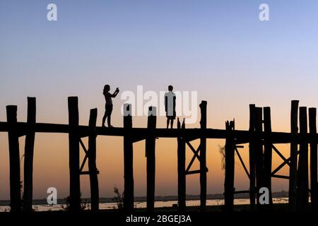 Silhouette eines Paares bei Sonnenuntergang auf U Bein Bridge, Amarapura, in der Nähe von Mandalay, Myanmar. Stockfoto