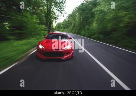 Superpower Red Rennwagen auf der Landschaft fahren durch Regenwälder Stockfoto