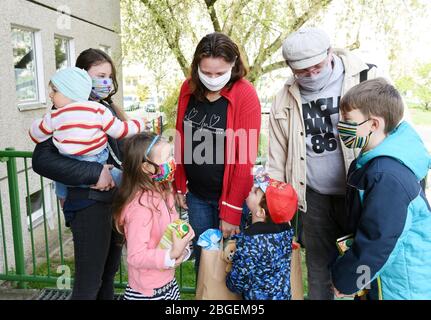 Leipzig, Deutschland. April 2020. Mit verpacktem Essen, das am Fenster der Heilsarmee im Kreis Paunsdorf verteilt wird, stehen Sandra (4. Von rechts) und Ronny Steglich (2. Von rechts) mit fünf ihrer acht Kinder am Eingang der Verteilstelle. Die Heilsarmee steht derzeit für die Leipziger Tafel ein, die vorerst nicht geöffnet werden kann. Lebensmittelspenden und ggf. selbstgenähte Mundschutz werden von Unternehmen in der Stadt und vom Bundesligaverein RB Leipzig verteilt. Quelle: Waltraud Grubitzsch/dpa-zentralbild/ZB/dpa/Alamy Live News Stockfoto