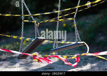 Dortmund, 21.4.2020: Mit Flatterband festgebundene Kinderschauen auf einem wegen der Coronavirus Krise (Covid-19, SARS-CoV-2) und zum Schutz vor Neuinfektionen gesperten Kinderspielplatz in einer Kleingartenanlage in Dortmund. --- Dortmund, 21. April 2020: Kinderschaukeln mit Bändern an einem Spielplatz in Dortmund gebunden. Geschlossen wegen der Coronavirus-Krise (Covid-19, SARS-CoV-2) und zum Schutz vor Neuinfektionen. Stockfoto